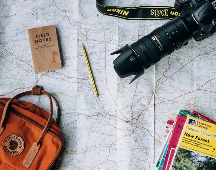 Pack items featuring camera notepad pencil and books on top of map