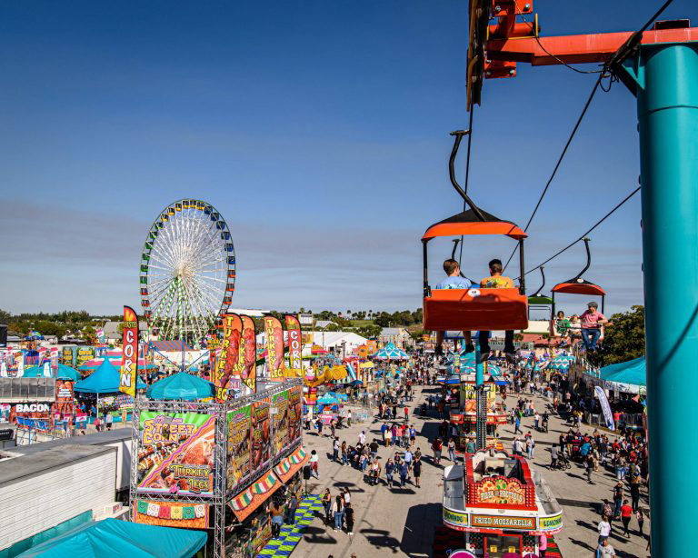 Travelers on weekend trip to carnival with ferris wheel in background and people riding rides