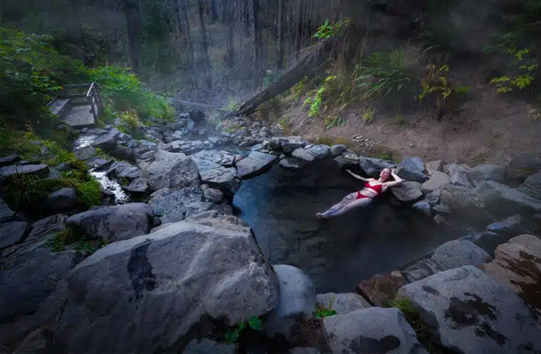 Woman soaking in natural hot spring in the forest