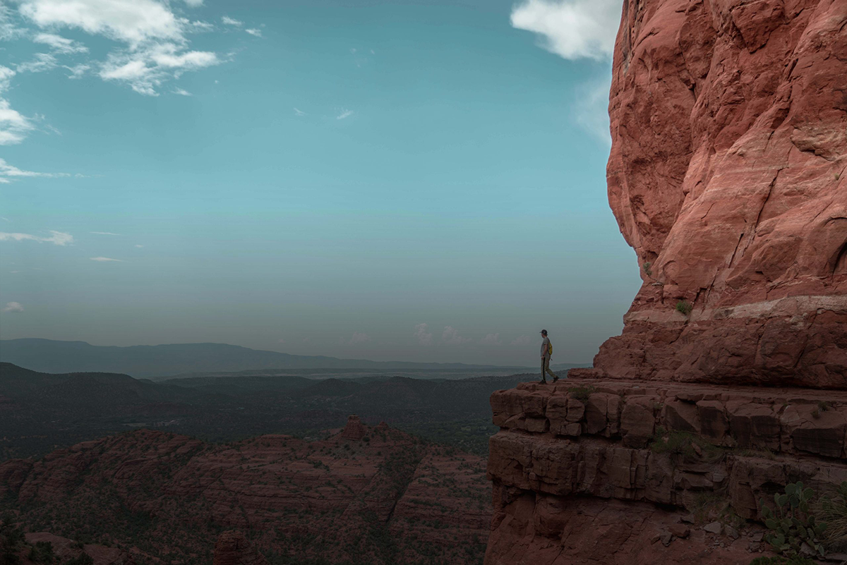 Traveler on an adventure getaway standing on the edge looking over a cliff