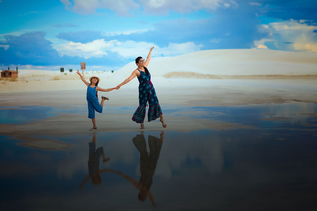 Woman and child dance above their reflection in pool of water