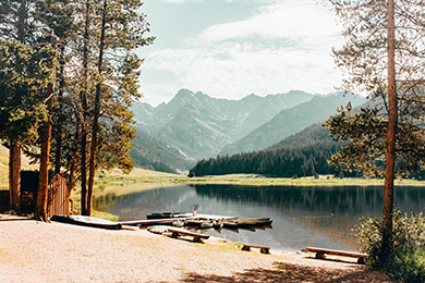 Ski towns are summer dream destinations for last minute travel. this is a photo of a ranch in vail colorado with a lake and the mountains in the backgruond.