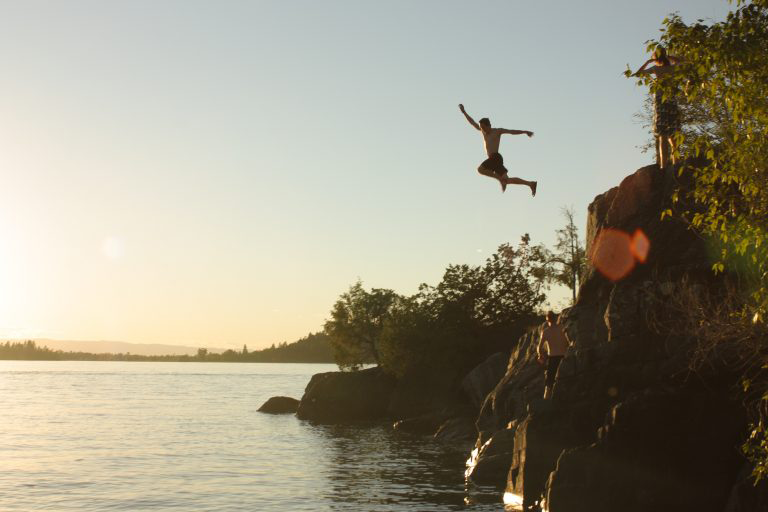 man jumping from cliff on a last minute vacation