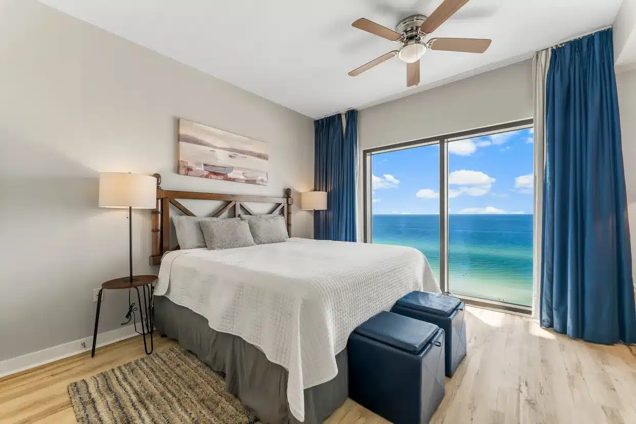 a view of a last minute vacation rental beach condo with the ocean seen out of the window and a bed in the forefront