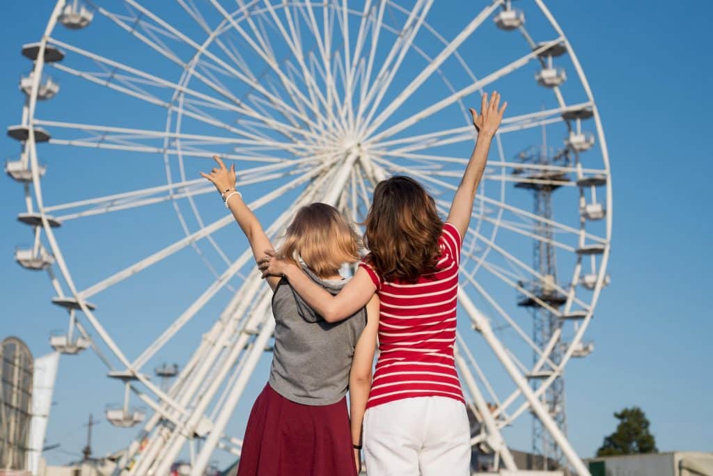 Mother and daughter posing in front of a ferris wheel