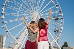 Mother and daughter posing in front of a ferris wheel