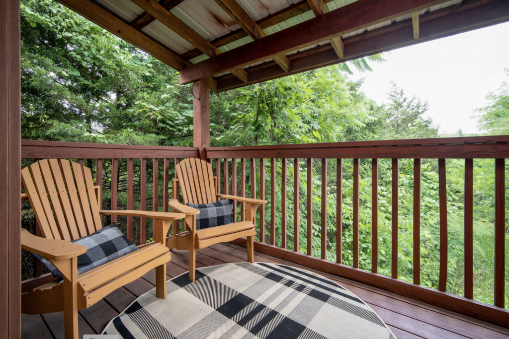Two chairs on a back porch overlooking the forest.
