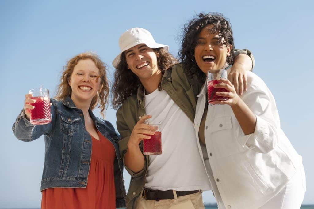 Three friends holding drinks and posing for a photo.