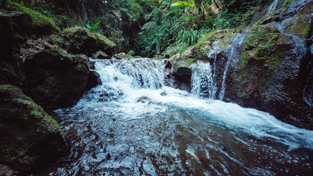 waterfall over green rocks