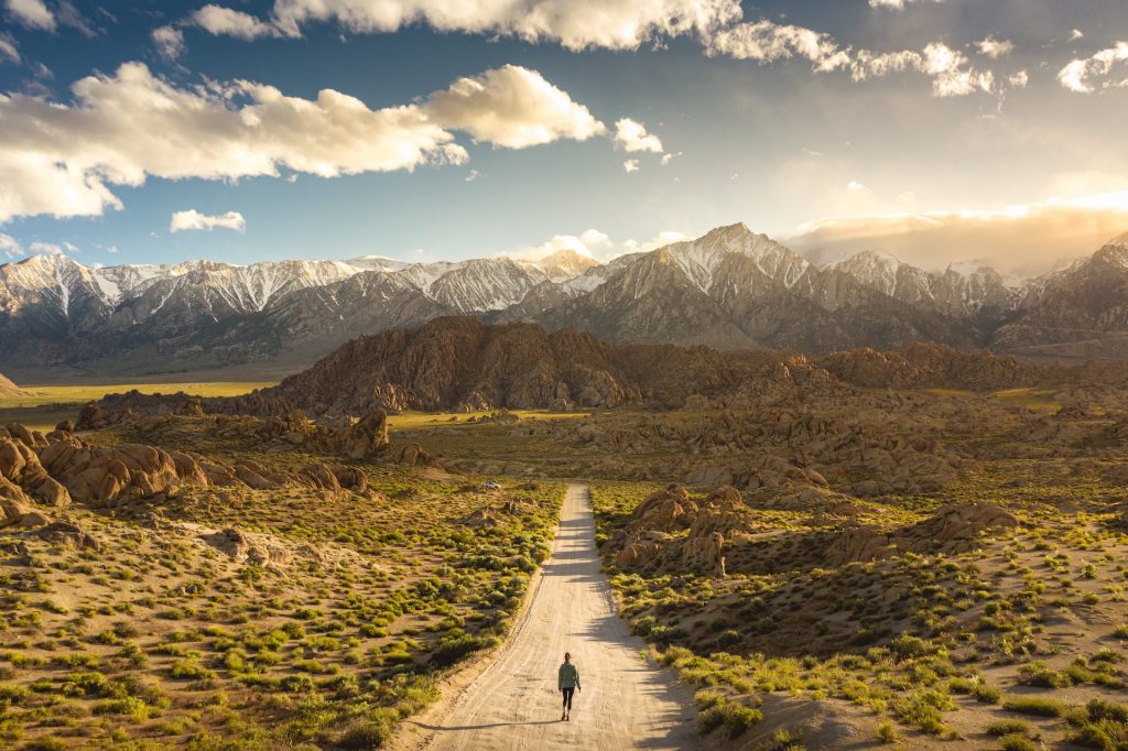 A person walking towards a vast mountainscape
