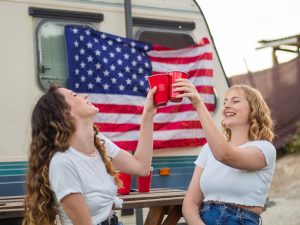 Women sitting in front of car with American flag