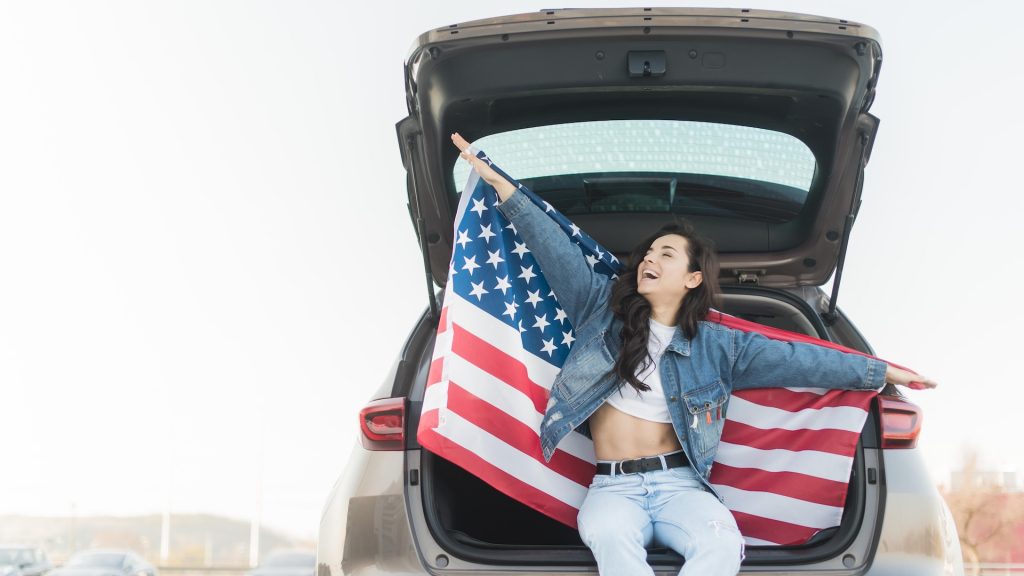 A woman sitting in her car with American flag