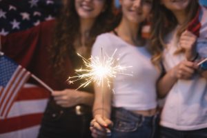 Girls holding a sparkler and American flag.
