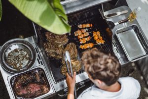 A man makes barbecue grill meat outdoors.