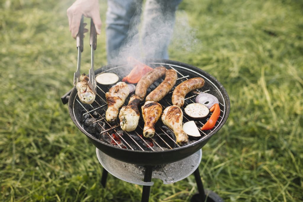 person cooking chicken on charcoal grill